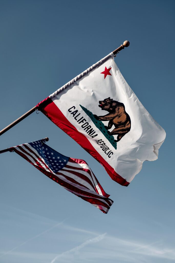 California and US flags waving against a clear blue sky in Santa Barbara, embodying American patriotism.