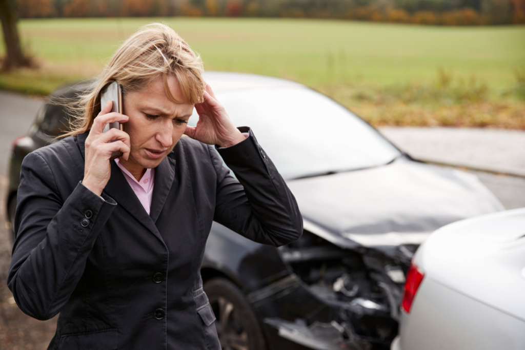 Woman on the phone near a damaged vehicle after a car accident in Burbank